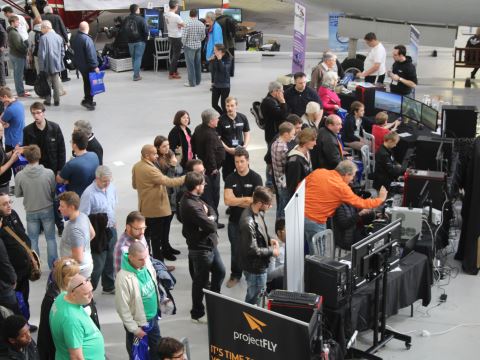 A crowd of visitors looking and trying out PC systems for flight sim