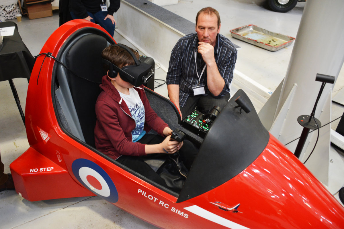 A younger visitor trying out a Hawk cockpit setup with VR